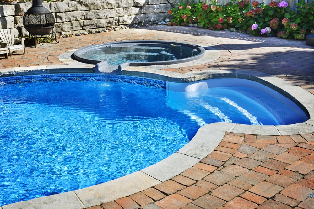 Outdoor in ground residential swimming pool in backyard with hot tub